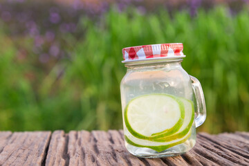 Detox water with lime in jar against rustic wood.