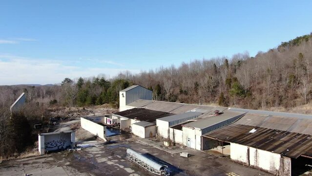 Aerial Drone Footage Orbiting Left around an Abandoned Warehouse on the Edge of a Forest.