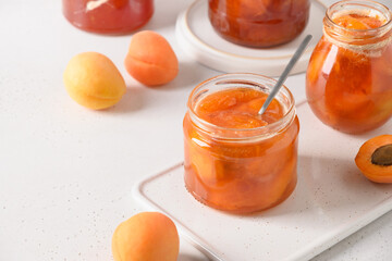 Apricot jam in glass jar on white background. Summer harvest and canned food. Copy space. Close up.