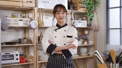 waist up, confident asian chef smiling at camera with arms crossed. background cozy home kitchen...
