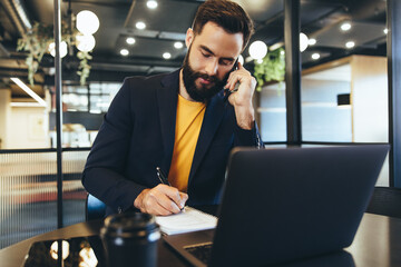 Businessman making notes during a phone call