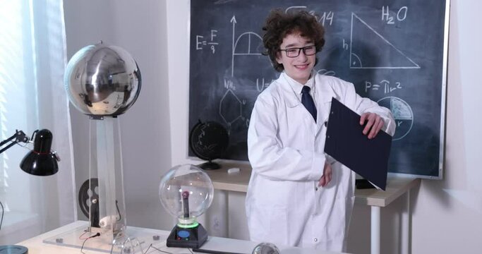 Physics science lab: handsome young scientist in white coat and glasses doing electrical tests. Child studying electrical discharges in a lab.