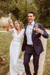 Happy smiling wedding couple walking with glasses of champagne in the hand. Bride and groom....