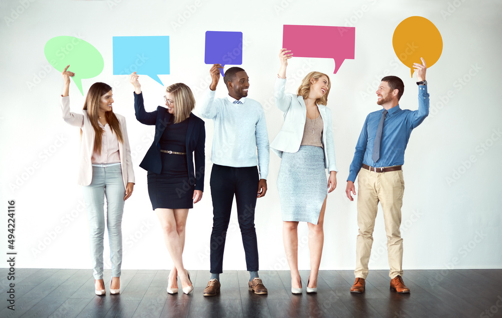 Wall mural Sorry what did you say. Shot of a group of work colleagues standing next to each other while holding speech bubbles against a white background.