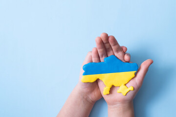 Yellow-blue colors flag Ukrainian map in childrens hands, top view
