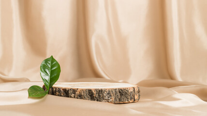 Wooden empty display with green leaf on beige textile, podium for natural cosmetic or product presentation, banner size