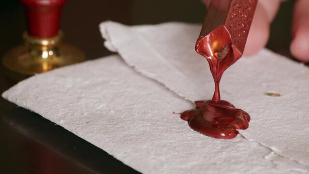 Hot wax drips on a piece of parchment in preparation for a wax seal