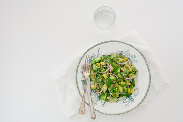Green vegetarian salad of avocado, cucumber, seeds, micro-greens and red onion on a white background. Space for text