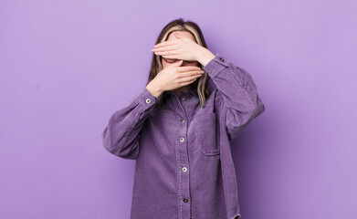 pretty caucasian woman covering face with both hands saying no to the camera! refusing pictures or...