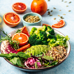 Healthy vegetarian dish with vegetables, avocado, blood orange, broccoli, watermelon radish, spinach, quinoa, pumpkin seeds. Buddha bowl. Balanced food. Delicious detox diet. Top view