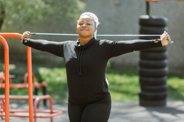 Afro-american plus size woman doing workout exercises session outdoor
