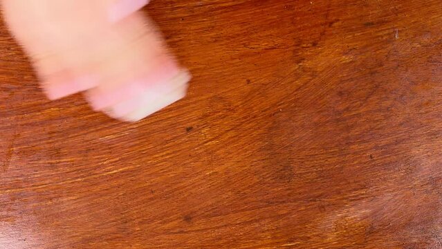 Top view of female hand using a paper towel dusting the wooden furniture. Clean your table for antistress purposes. Household chores. Simple duties at home.