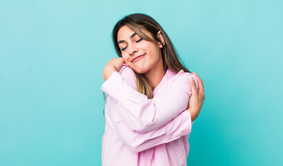 pretty hispanic woman feeling in love, smiling, cuddling and hugging self, staying single, being...