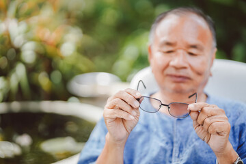 The old man held up his glasses and looked before wearing it with a smile on his face.