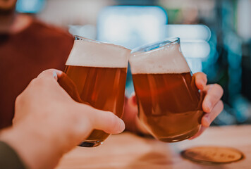 two glass of beer in hand. Beer glasses clinking in bar or pub