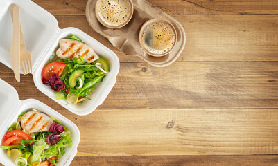 Lunch boxes with salad, grilled chichen and coffee on wooden table. Copy space, top view.