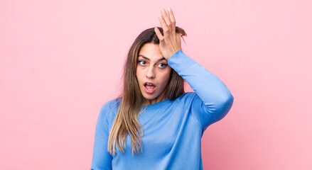 pretty hispanic woman raising palm to forehead thinking oops, after making a stupid mistake or...