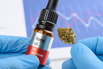 Scientist hold hemp full spectrum oil in one hand and CBD cannabis flower in other