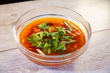 traditional Ukrainian homemade borscht in a transparent plate and herbs