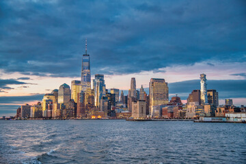 Sunset skyline of Downtown Manhattan as seen from a ferry boat tour around New York City. - obrazy, fototapety, plakaty