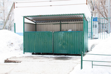 a place for a garbage container with a green gate on the street