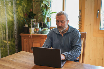 Senior man using computer laptop at home