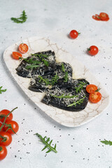 Fototapeta na wymiar Black pancakes stuffed with red salmon caviar