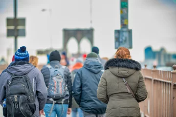 Gordijnen People walking on the promenade of the famous Brooklyn Bridge in winter season, back view. New York City, NY - USA. © jovannig