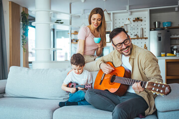 Single Father At Home With Son Teaching Him To Play Acoustic Guitar at home. Getting it right together. Shot of a boy learning to play guitar from his father