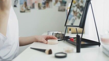 Home beauty salon. A close-up shot of an unrecognizable female hand applying powder to a brush, doing everyday makeup at home