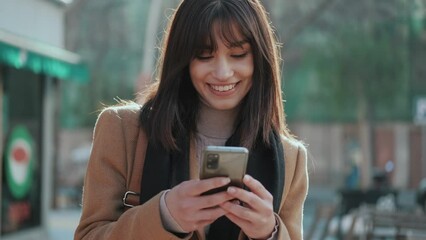 Video of pretty young woman using her mobile phone while drinking cup of coffee walking the streets of the city. - Powered by Adobe