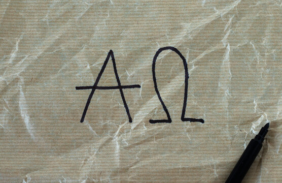 Alpha and Omega letters handwritten on crumpled paper with black marker. Top view, a closeup. The Christian biblical concept of God Jesus Christ is the First and Last. Prophecy from Bible Revelation.