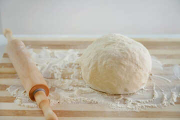 Close-up of rolling pin and dough on wooden table with flour. Basic needs and rising of prices concept.