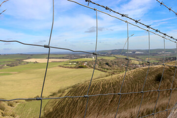 Beautiful pastoral view from countryside behind the wire fences. Hiking route. Unfocused natural landscape.