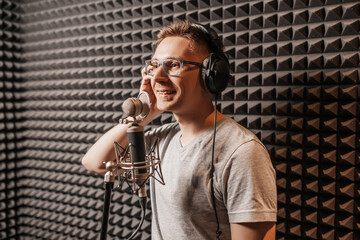 The vocalist sings in the studio in a microphone. Man in headphones writes a podcast, an audiobook....