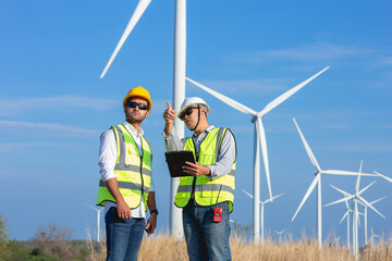 A team of Asian male engineers working together at wind turbine generator farm.