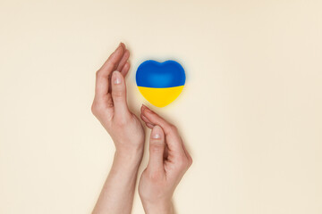 Heart with print the national flag of ukraine in female hand. Flat lay. Copy space.