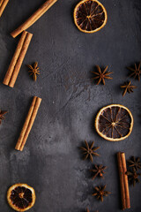 Spices, cinnamon, dried orange, anise on a black, old textured background. Space for text.