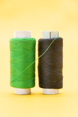 green and black color yarn or spool thread over on yellow background