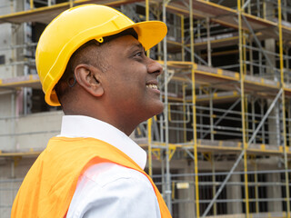 Profile portrait of a smiling Indian civil engineer or factory worker wearing a safety helmet and looking aside