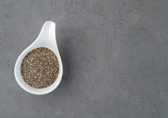 Chia seeds in a white bowl over stone background with copy space