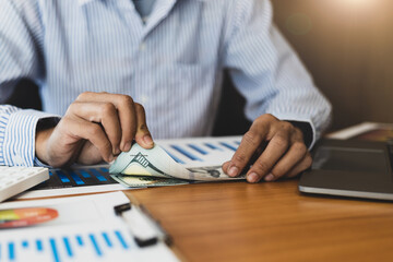 Close-up businessman holding banknotes counting money.