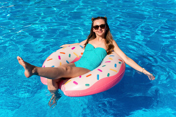 young woman in bikini swims on the inflatable water donut in the swimming pool