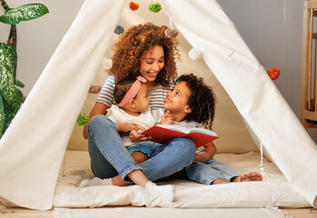 Cute   african american family mom and kids   reading book in play tent