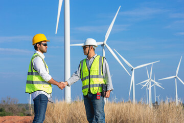 Two man Asian wind turbine engineers shaking hands after successful work together.