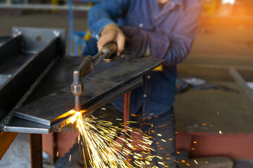 Close up hand a worker holds the gas cutting head to cut the steel plate in fabrication work:...