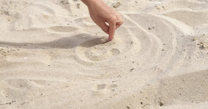 Drawing fingers on shore. A teen finger drawing on the clean sand something during summer vacation.