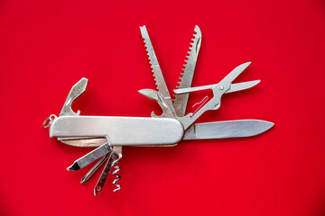 Metallic swiss knife isolated on red