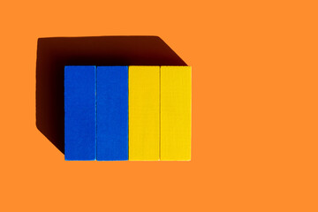 top view of colorful blue and yellow blocks on orange background, ukrainian concept.