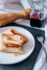 Three delicious spring rolls for breakfast. Russian pancakes with currant jam. Place for text.